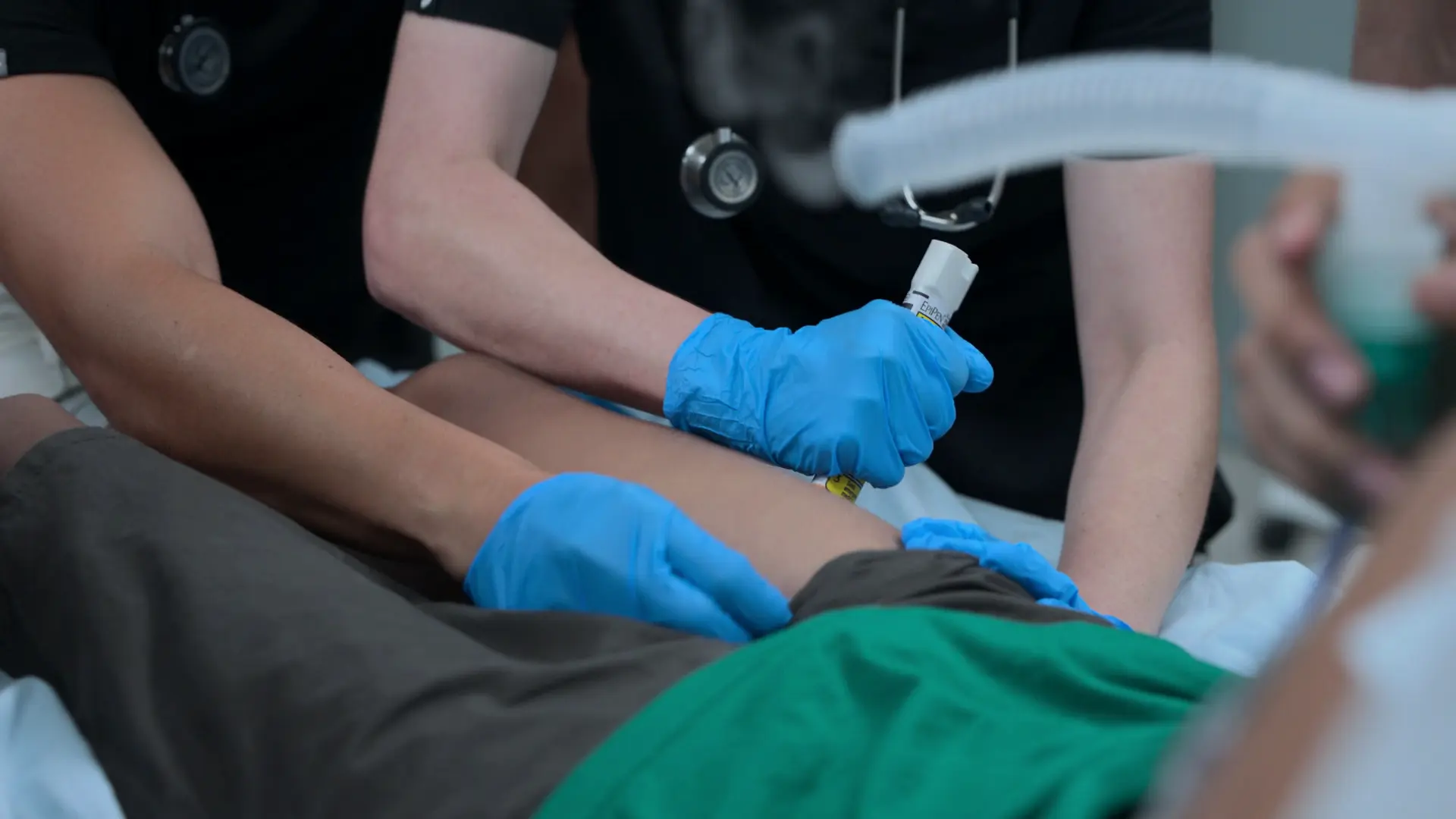 Mel administrant un stylo auto-injecteur d'adrénaline en intramusculaire (IM) dans la face antérolatérale de la cuisse du patient.