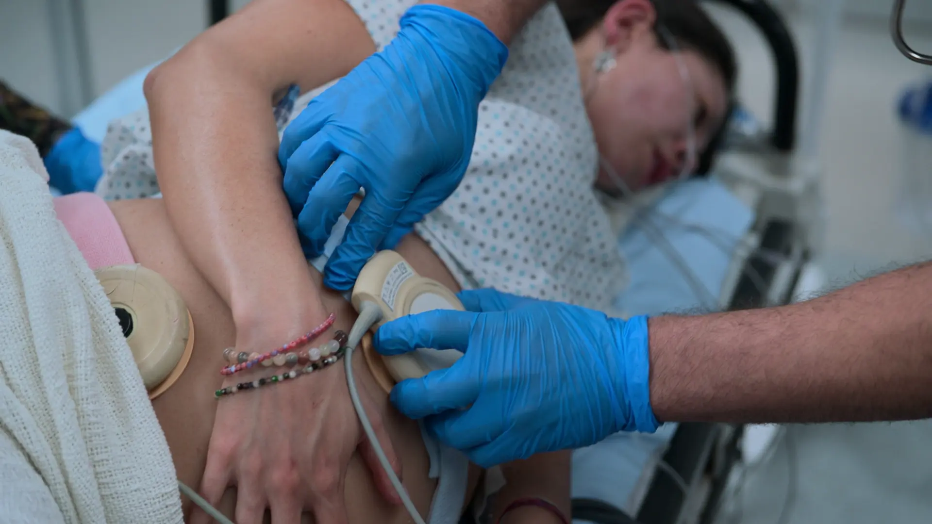 Mise en place des capteurs de cardiotocographie (CTG) sur l'abdomen maternel.